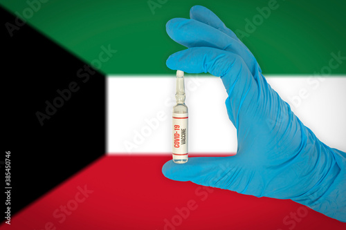 New coronavirus vaccine with the flag of Kuwait in the background. Kuwait medical research and vaccine development center. Doctor holding coronavirus vaccine in his hand.