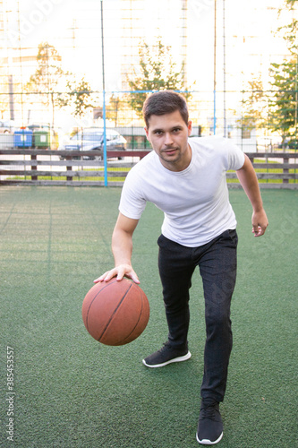 Young man in a white T-shirt playing basketball © Alexandru