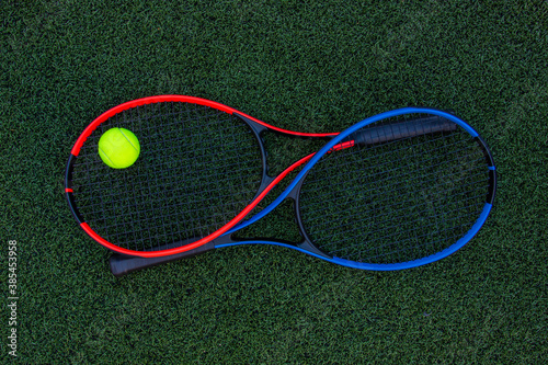 Tennis rackets with ball on green grass background