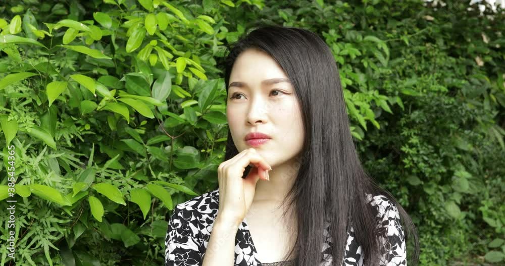 Chinese woman deep in thought in front of a green background Chinese woman deep in thought in front of a green background