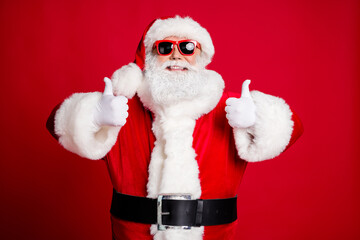 Portrait of his he nice handsome content glad cheerful cheery bearded Santa showing two double thumbup cool agree deal done isolated over bright vivid shine vibrant red color background