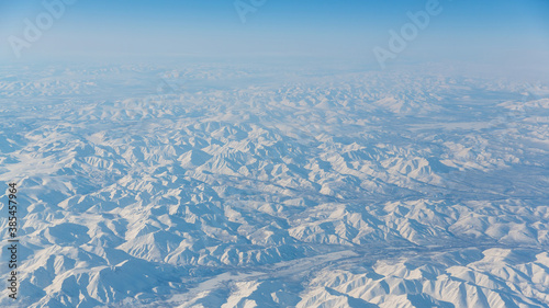 Aerial view of snow-capped mountains. Beautiful panorama of the highlands. Winter mountain landscape. Top view of the Kolymsky Ridge (Gydan). Kolyma Mountains, Magadan Region, Siberia, Far East Russia