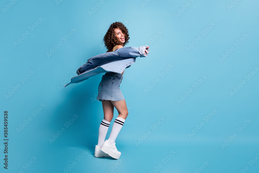 Obraz premium Full size photo nice energetic active lady model turn round fly jacket dancing party clothes brand advert concept wear green crop top denim shirt skirt isolated pastel blue color background