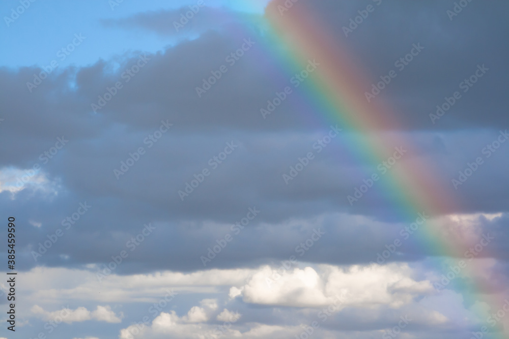 Rainbow formed after rain with clouds and blue sky in the background