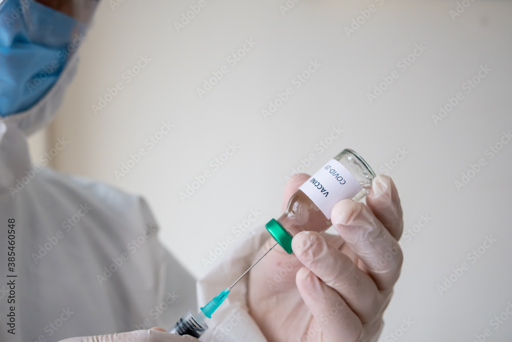 Doctor holding the covid-19 vaccine with his fingers. Vaccine and syringe in hand. Doctor holding the covid-19 vaccine with his fingers. Vaccine and syringe in hand.