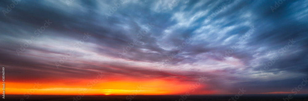 Dramatic sunset autumn sky panorama - the moment before sunset among the sky covered by black clouds 