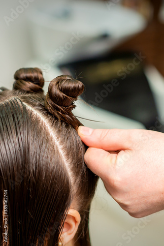 Young woman receives process of hairstyle by hairdresser at beauty hair salon
