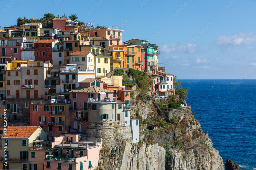 City built on a cliff overlooking the sea. Manarola in the Cinque Terre area in Italy. Colorful residential buildings on the blue sea.
