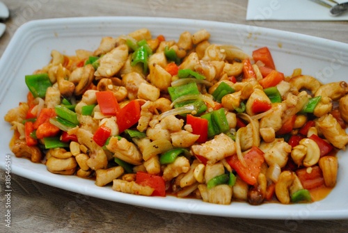 Kung Pau Chicken, a spicy, stir fried Chinese dish made with cubes of chicken, peanuts, vegetables, and chili peppers. Wooden background. Top view. 