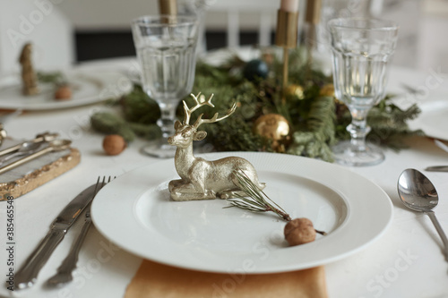 Christmas or New Years celebration party table setting. Plate with golden deer, cutlery and glasses
