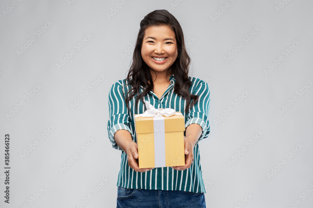 birthday present and surprise concept - happy asian young woman with gift box over grey background birthday present and surprise concept - happy asian young woman with gift box over grey background