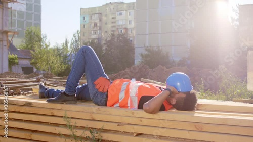 In a construction site worker Afro American in a break time take a nap outside over some woods he wake up take his safety helmet and going to work