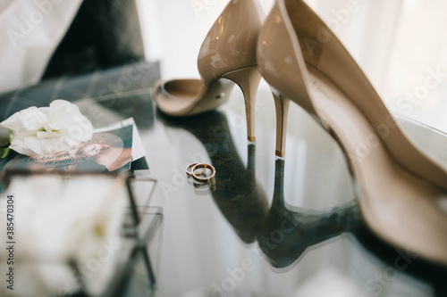 wedding shoes and rings on glass table