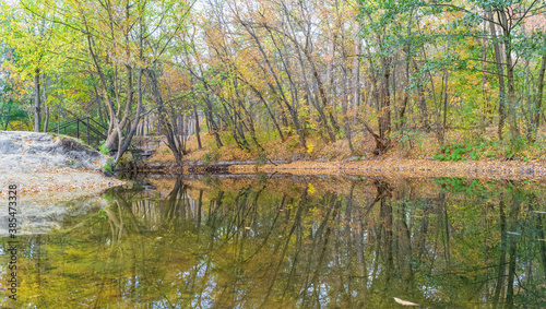 Autumn landscape in the forest with a bridge and reflection near the Kharkov river