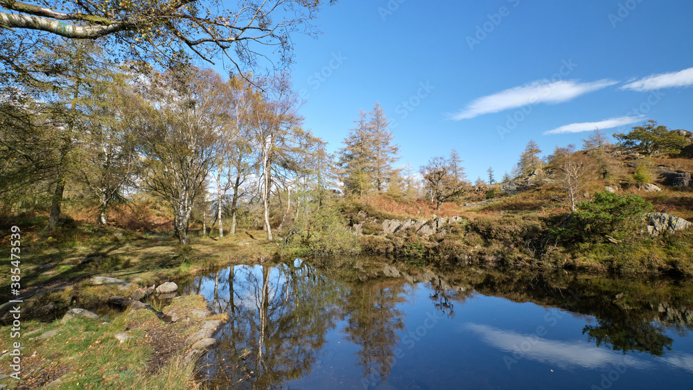 Autumn colours reflected in a Lake District tarn above derelict slate quarries at Hodge Close