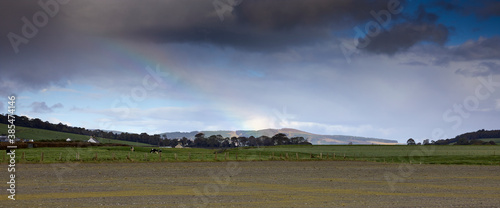 A rainbow begins to form in the light drizzle on the hills looking inland from Etterick Bay on Bute.