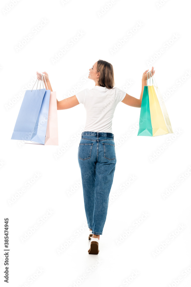 back view of young woman in jeans holding shopping bags isolated on white back view of young woman in jeans holding shopping bags isolated on white