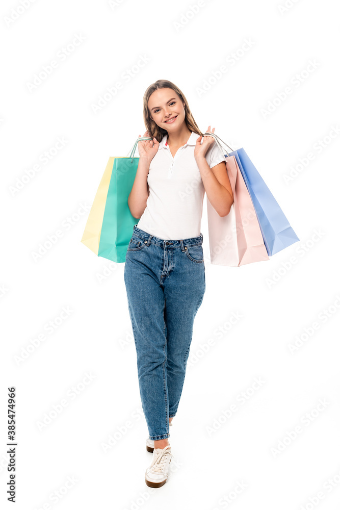 young and pleased woman in jeans holding shopping bags isolated on white young and pleased woman in jeans holding shopping bags isolated on white