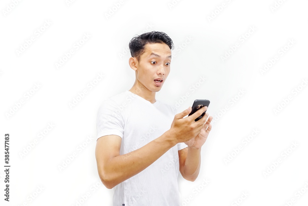 Young asian man holding smartphone and surprised by notification on his smartphone about discount or cash back from online shop. Millennial and business concept. Young asian man holding smartphone and surprised by notification on his smartphone about discount or cash back from online shop. Millennial and business concept.