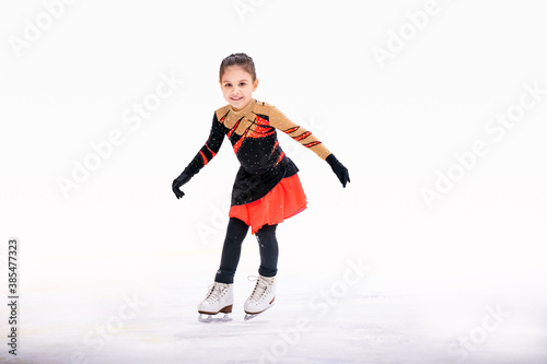 little girl figure skater in red black beautiful dress with smile skates on the ice on an indoor skating rink. © Maria Moroz