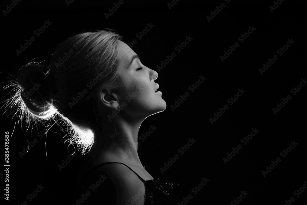 Young beautiful blond glamorous woman in black over dark background Young beautiful blond glamorous woman in black over dark background
