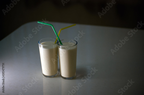 Milkshakes with straws, illuminated by artificial light in a dark room.