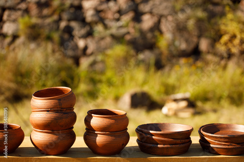 clay plates stand in rows on a wooden shelf photo