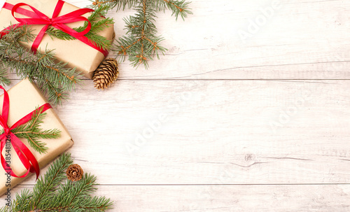 Christmas background, wallpaper. Happy New Year composition. Christmas gift with red ribbon, pine cones, fir branches on wooden flat