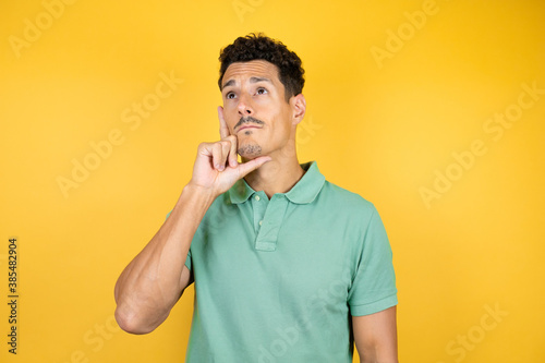 Young handsome man wearing green casual t-shirt over isolated yellow background thinking and looking to the side