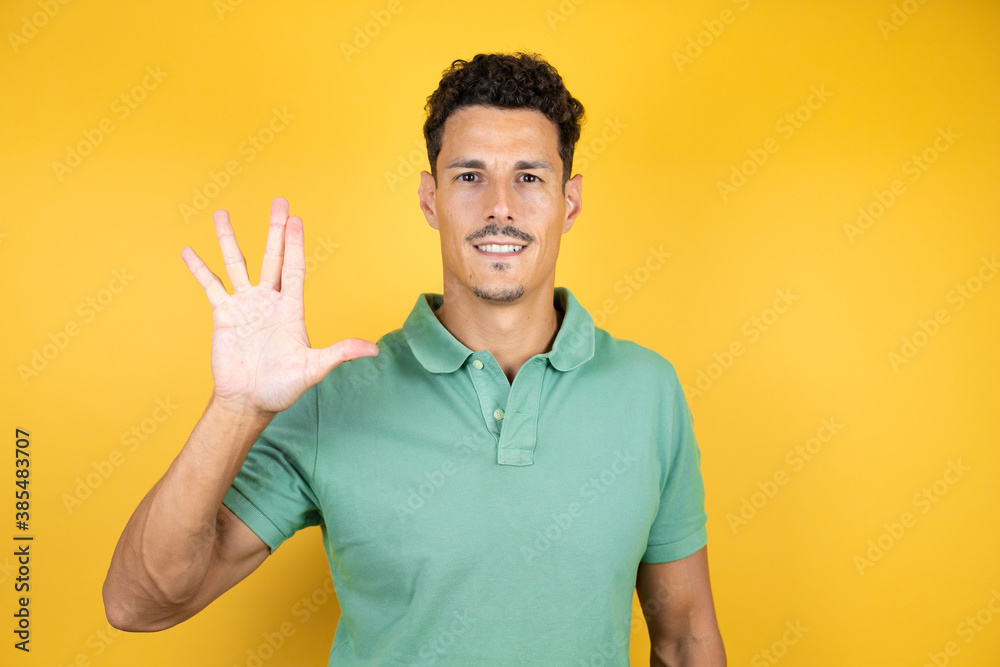 Young handsome man wearing green casual t-shirt over isolated yellow background doing star trek freak symbol Young handsome man wearing green casual t-shirt over isolated yellow background doing star trek freak symbol