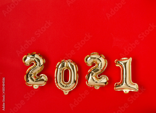 Happy New year 2021 celebration. Gold foil balloons numeral 2021 on red background. Holiday background Happy New Year, flat lay, top view, copy space.