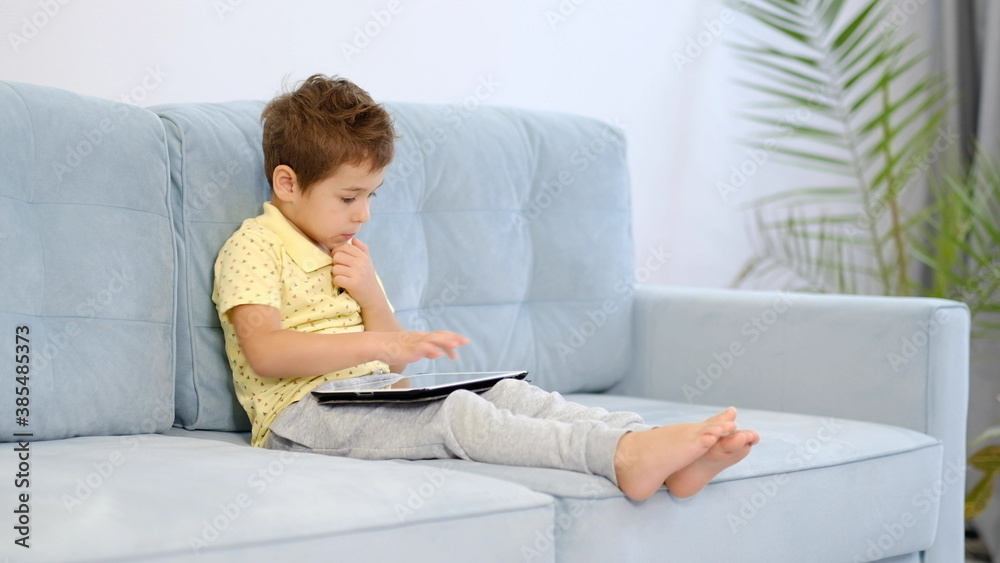 A little boy uses a tablet for games and cartoons A little boy uses a tablet for games and cartoons