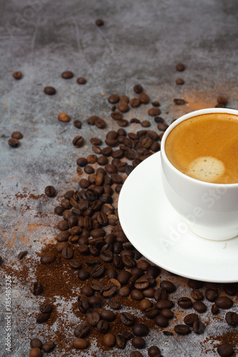 black coffee in white cup and coffee beans on gray background.