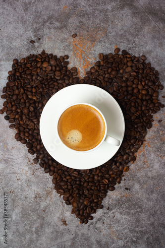 heart shaped cup of black coffee in coffee beans.