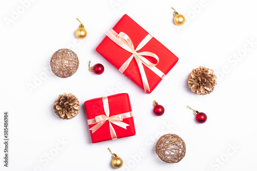 Christmas composition. Red gift box, pine cones, gold and red ornament decorations on white background. Winter holidays concept. Top view