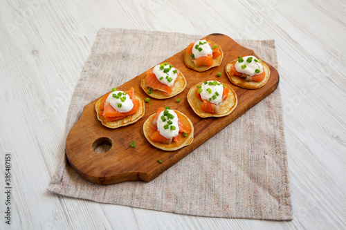 Homemade Blini with Smoked Salmon, Creme and Chives on a rustic wooden board, low angle view.