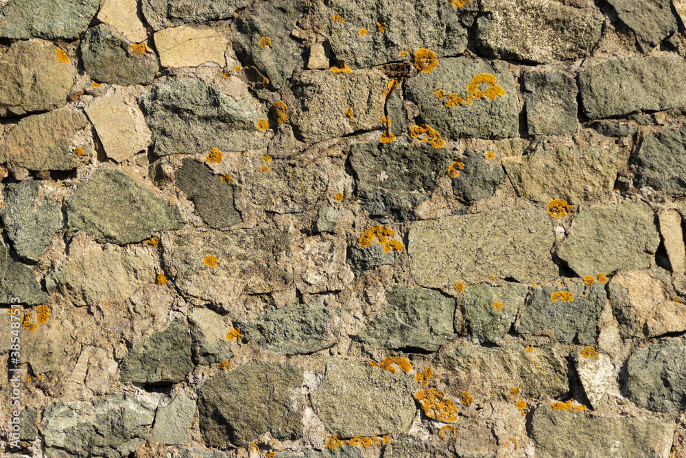 The surface of an old stone wall, masonry of uneven wild hewn stones. The surface of an old stone wall, masonry of uneven wild hewn stones.