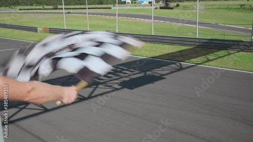 Woman holding and waving the checkered race flag, moto racers passing. Sport concept.  photo