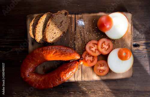 Sausage on a wooden Board,with slices of tomatoes,onions with slices of bread,still life photo