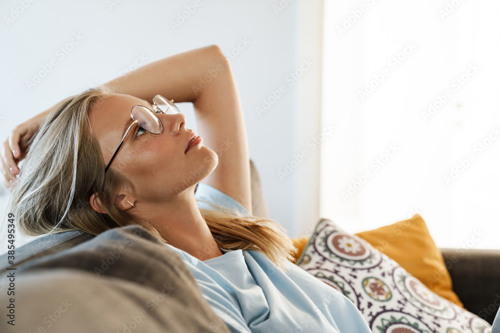Fototapeta premium Beautiful relaxed girl in eyeglasses resting on couch at home
