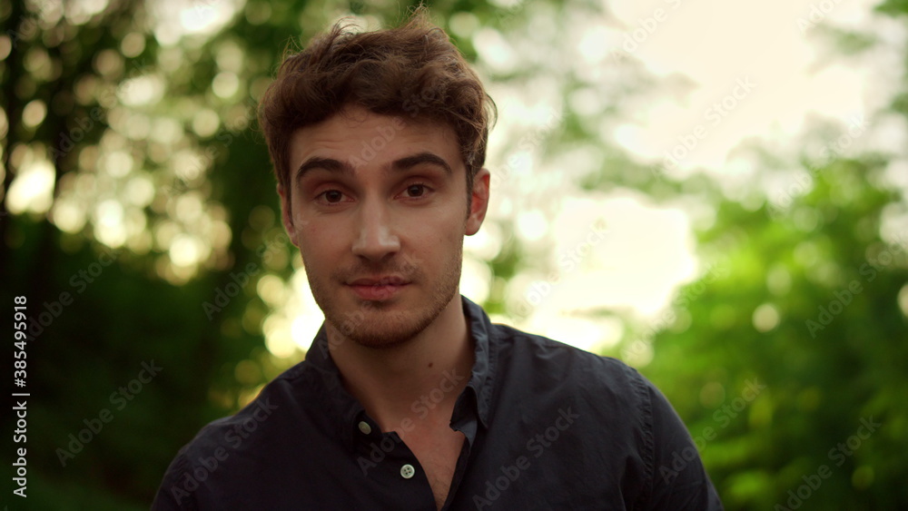 Charming man looking at camera outdoors. Attractive male person posing on road