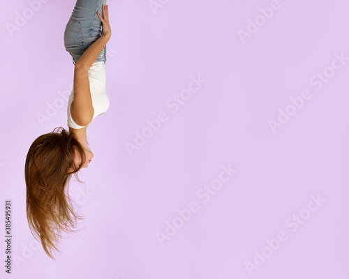 Beautiful girl 19 years old on pink background in jeans and light T-shirt, long flying hair, closed eyes. Upside down view. Concept of dreams, inspiration. Great photo for advertising. Copy space photo
