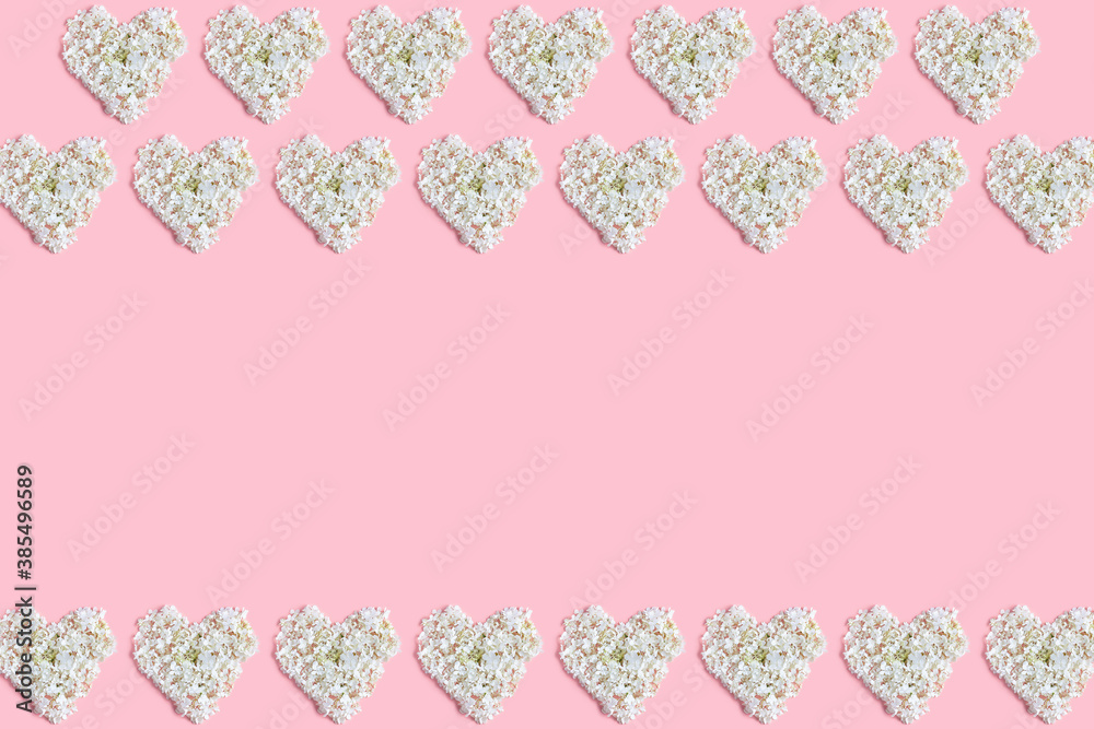 the floral concept in pastel colors. frame made hearts of white hydrangea flowers on a pink background. Valentine's day layout. space for text, top view