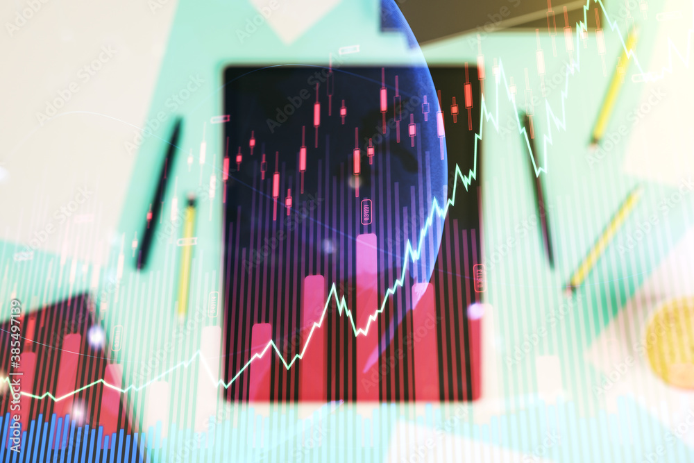 Multi exposure of abstract financial graph with world map and modern digital tablet on desktop on background, top view, financial and trading concept