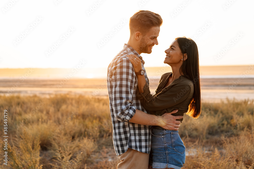 Romantic happy couple hugging and smiling while strolling on nature Romantic happy couple hugging and smiling while strolling on nature