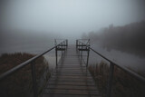 Pier on a foggy morning lake with mystical fog in autumn