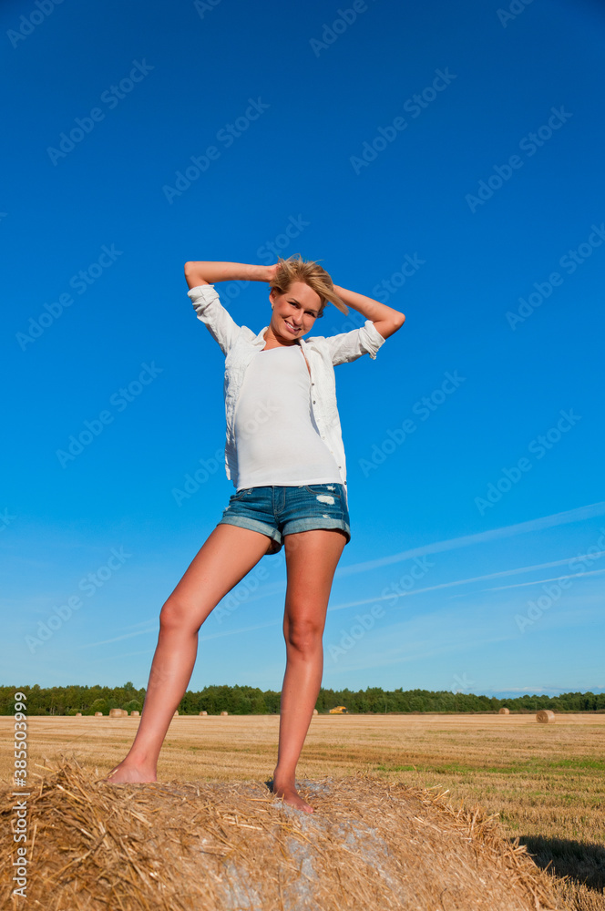 Beautiful woman in short posing on a wheat bale Beautiful woman in short posing on a wheat bale