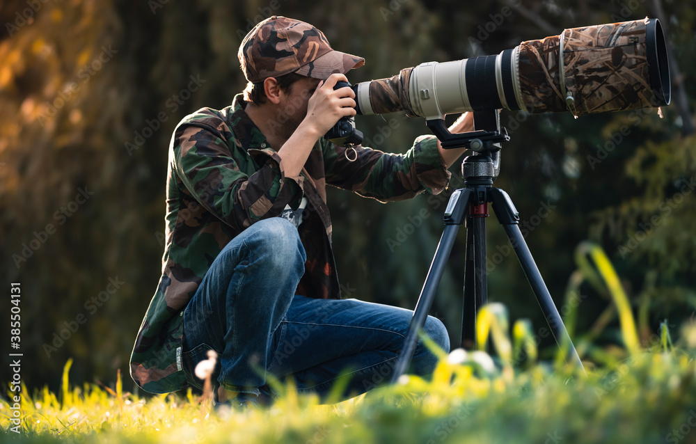 wildlife photographer using telephoto lens with camouflage coating  photographing wild life using gimbal head on tripod. professional  photography equipment for cinematic shooting in the nature outdoor foto de  Stock | Adobe Stock