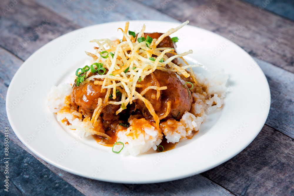 Fresh beef meatballs served with a sauce over a bed of rice Fresh beef meatballs served with a sauce over a bed of rice