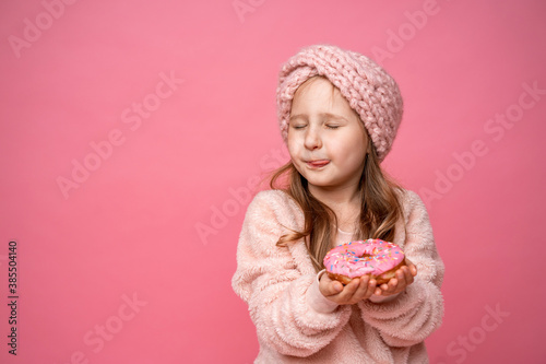 little girl, closing her eyes, licking her lips with tongue, wants to eat donut